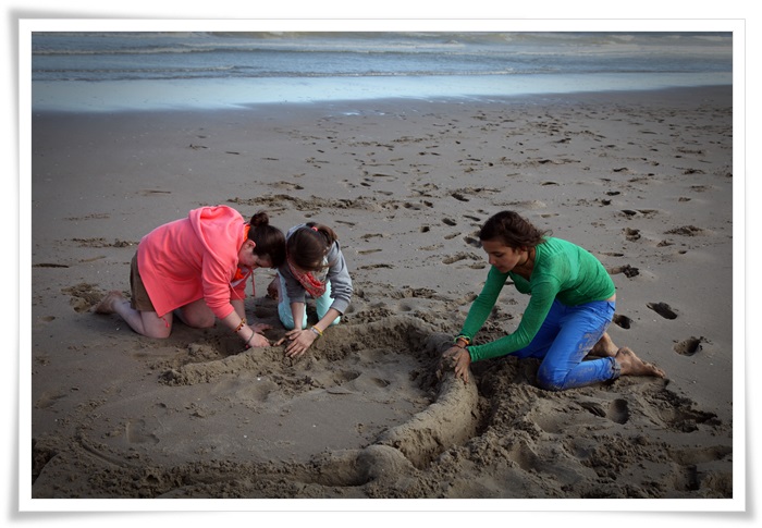 Drie meisjes maken een zandkasteel