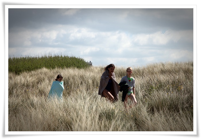 Drie meijes wandelen door het helmgras