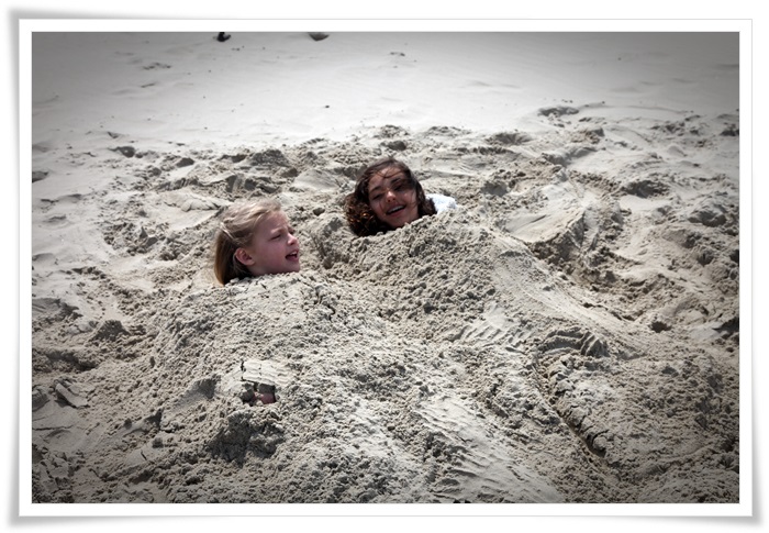 Twee meisjes onder het zand van het strand